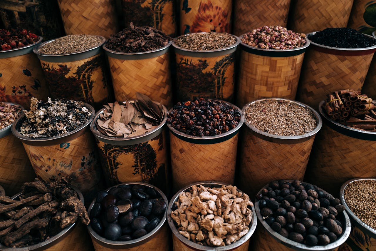 A vibrant display of various spices and herbs in woven baskets at a market stall.